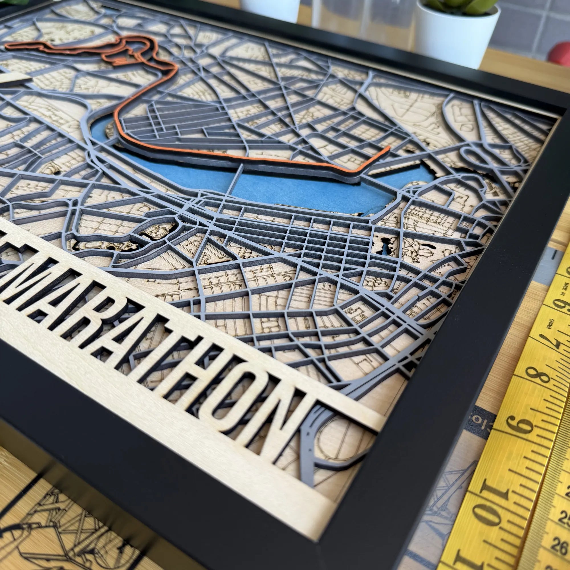 3D laser-cut map of a marathon route with 'Marathon' text on a wooden plaque.