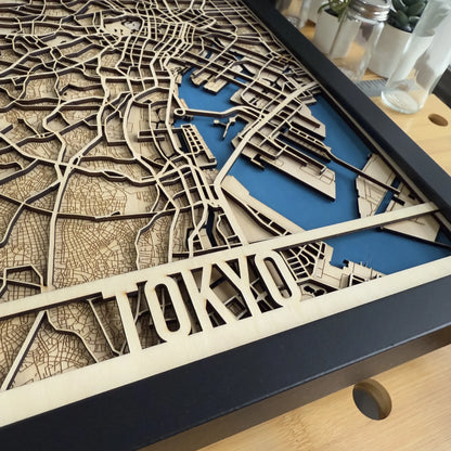 Wooden laser-cut map of Tokyo with blue highlighting on a wooden surface.